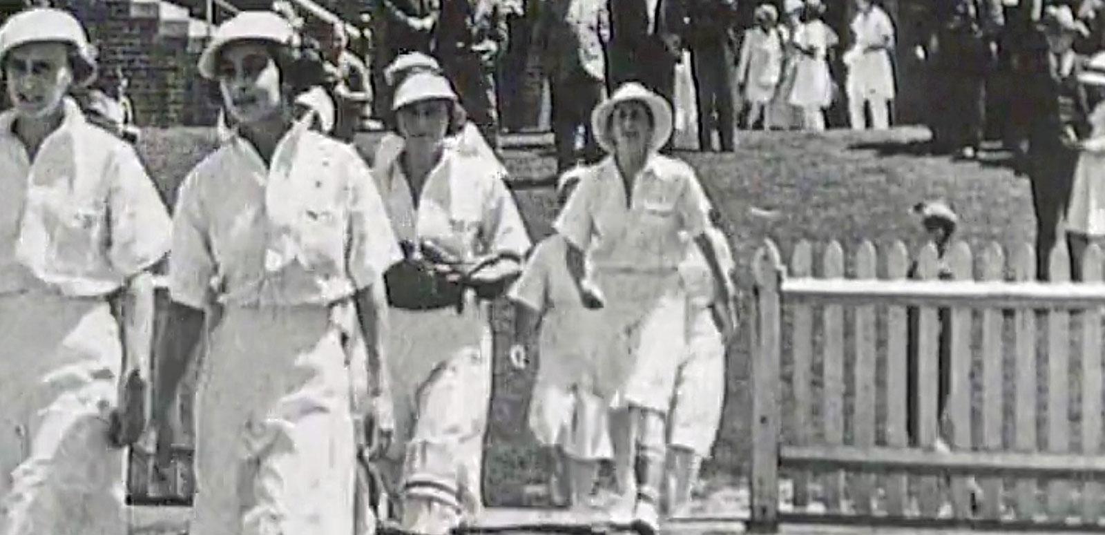 Women's Cricket latest post hero image A team of women cricketers from the 1930s walking onto a cricket field in white uniforms.