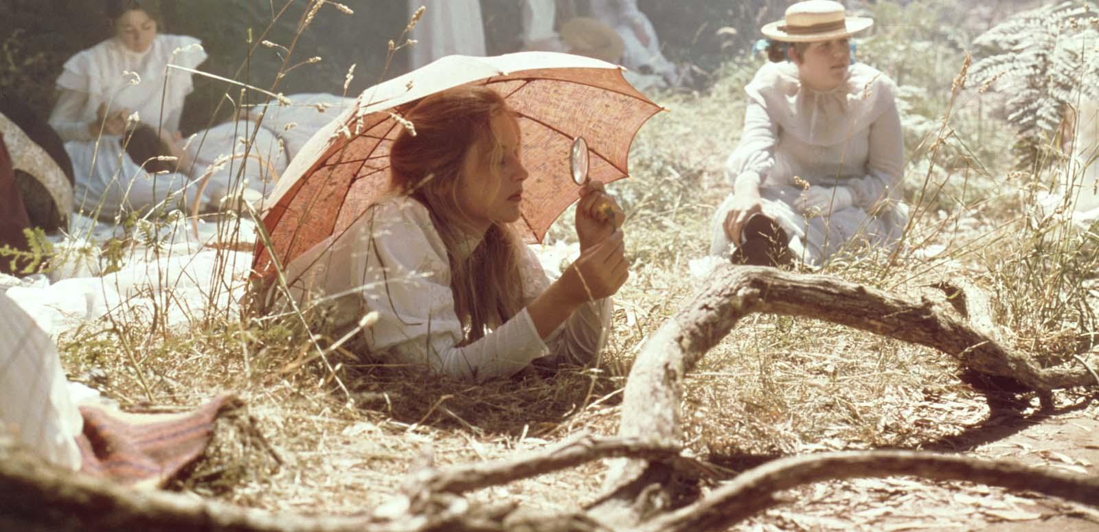 Miranda rests on the grass under a parasol and looks through a magnifying glass in a scene from the film Picnic at Hanging Rock Miranda rests on the grass under a parasol and looks through a magnifying glass in a scene from the film Picnic at Hanging Rock