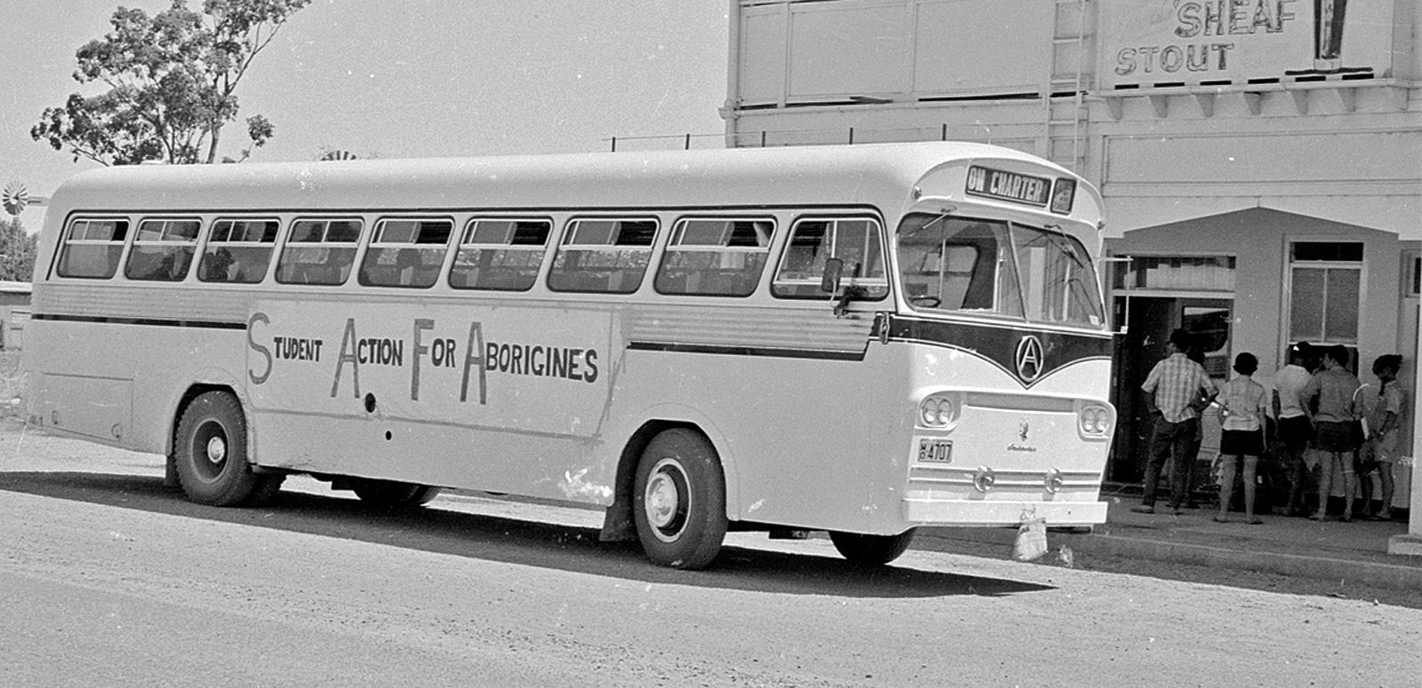 A large bus pictured from the side. It has a sign on the side that reads 'Student Action For Aborigines'.