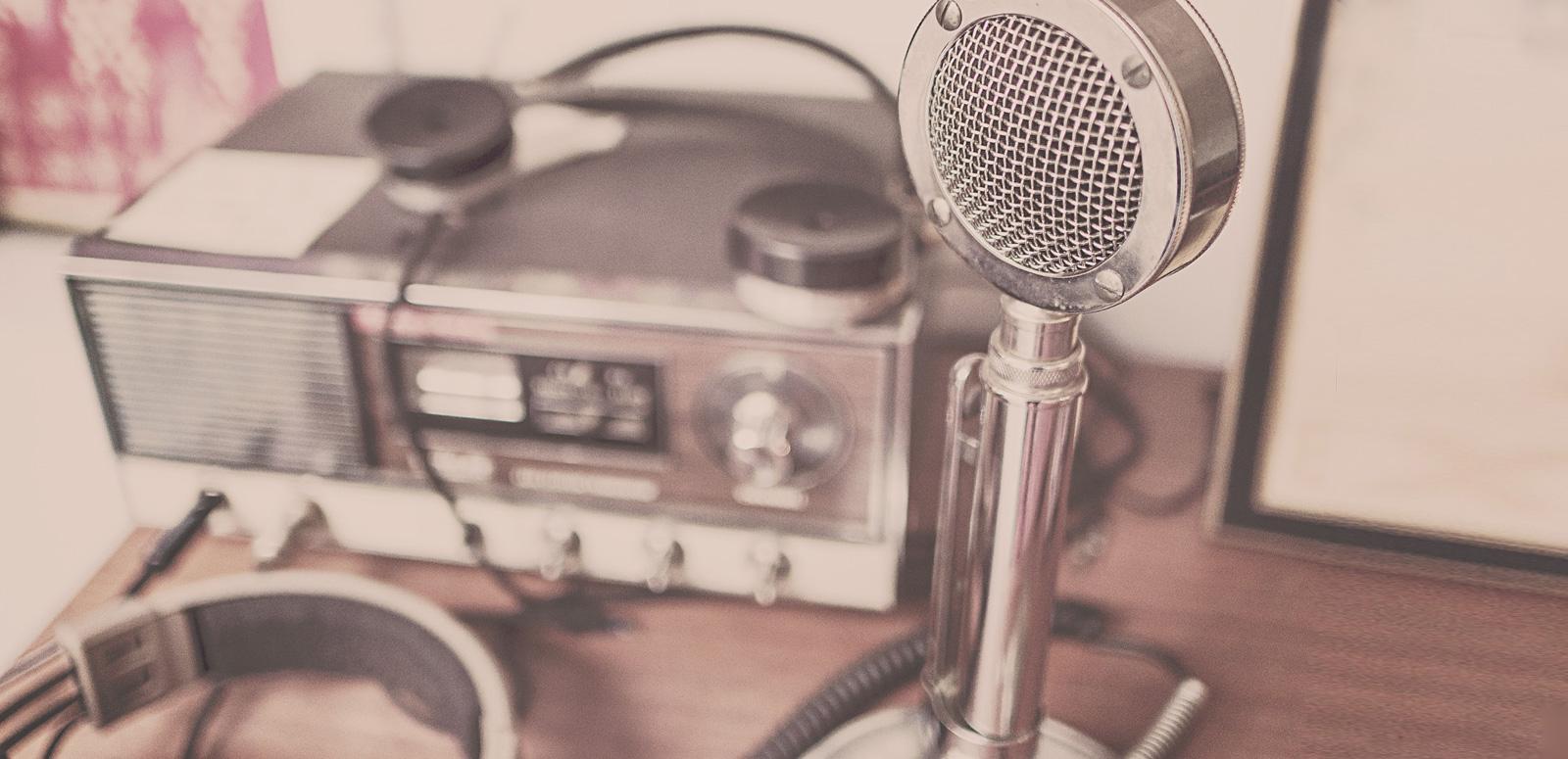 A radio microphone and audio recorder sitting on a desk.