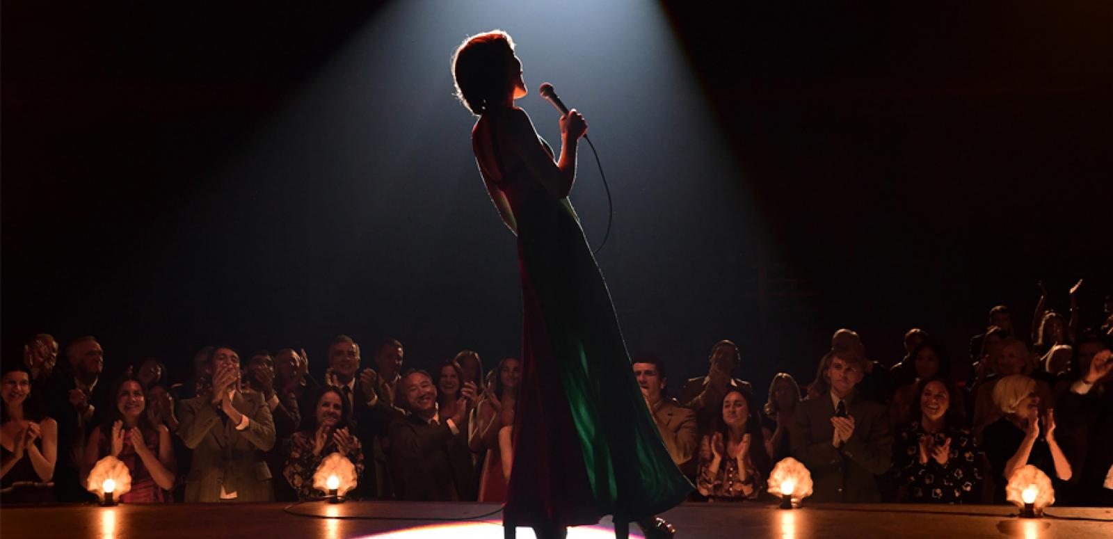 Female singer on stage silhouetted against an audience Female singer on stage silhouetted against an audience