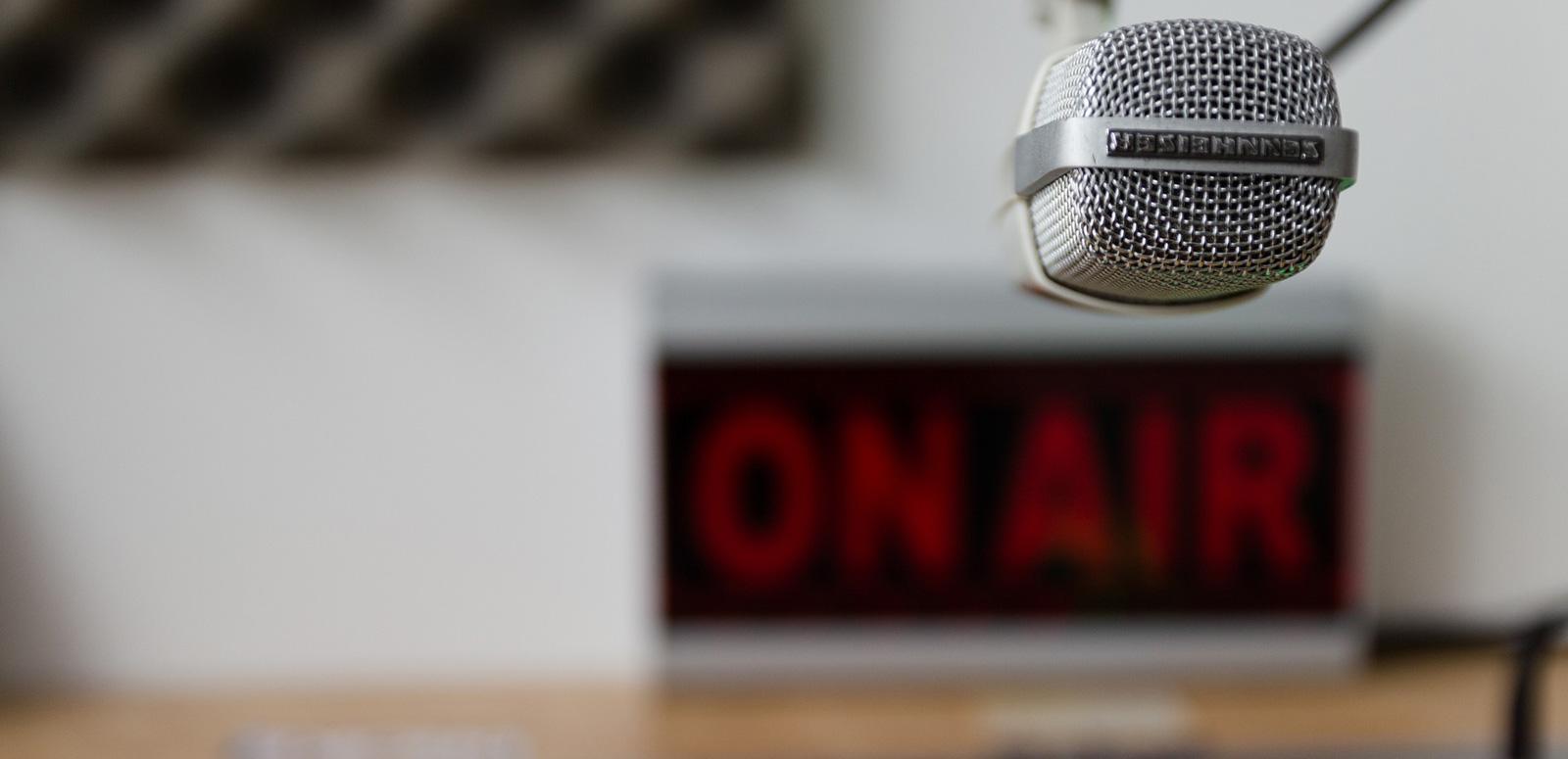A radio microphone in front of an On Air sign in a radio station studio