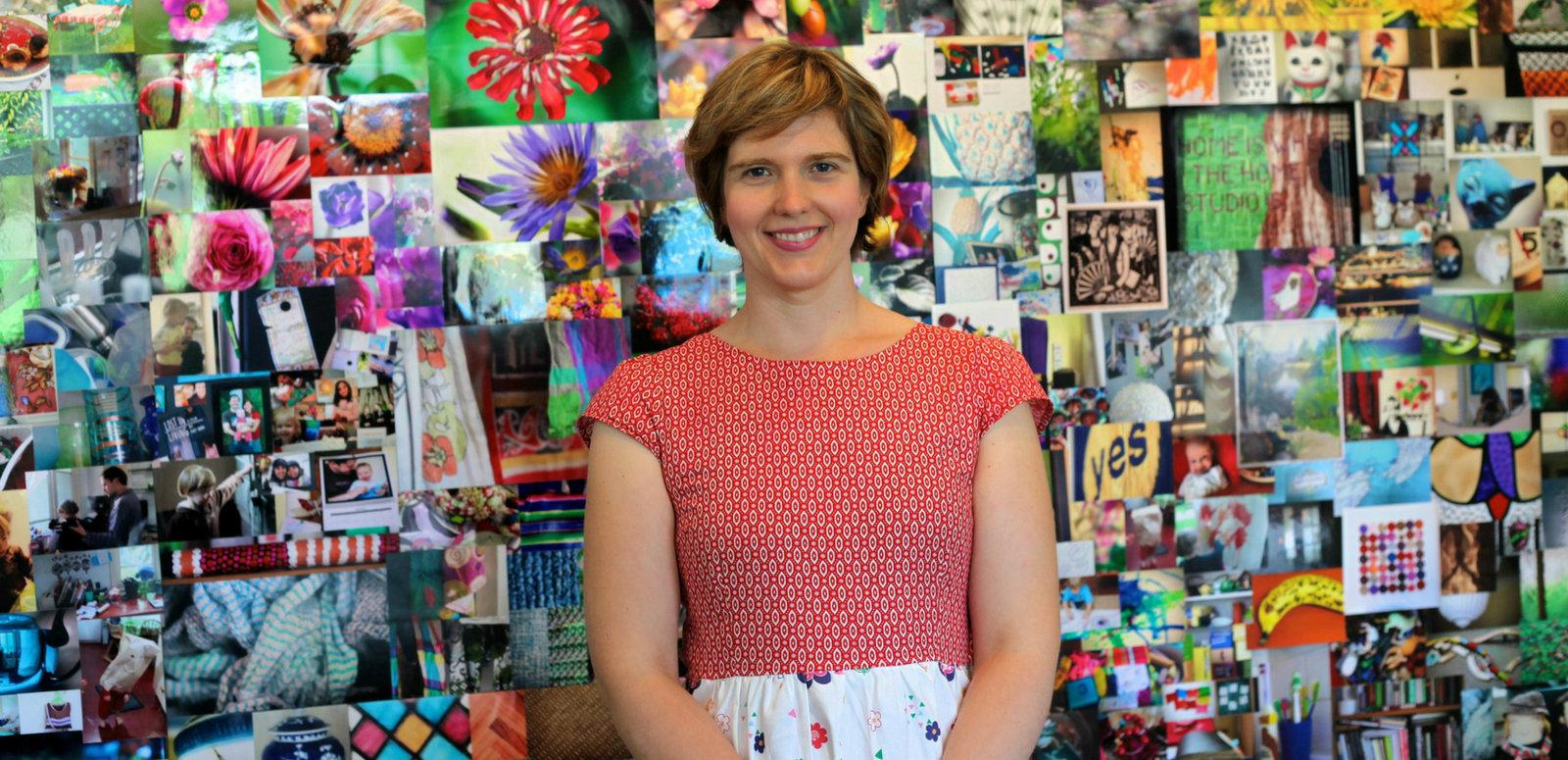 Beth Taylor blog hero image Beth Taylor standing in front of her exhibition of 1000 photos on the topic of 'home'
