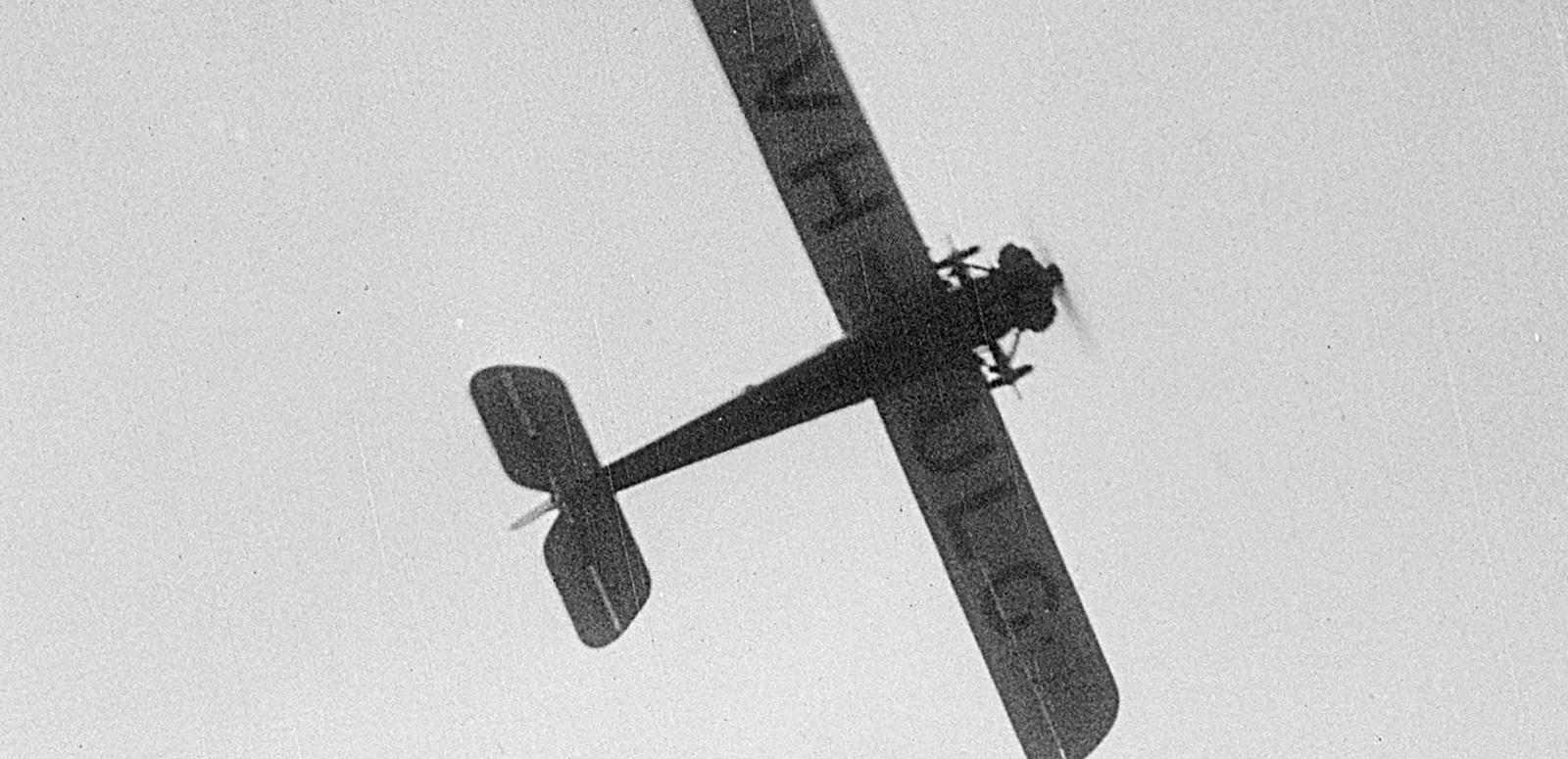 An early 20th century aeroplane flies overhead, seen from below with the letters VH-ULG visible on the underside of the wings An early 20th century aeroplane flies overhead, seen from below with the letters VH-ULG visible on the underside of the wings