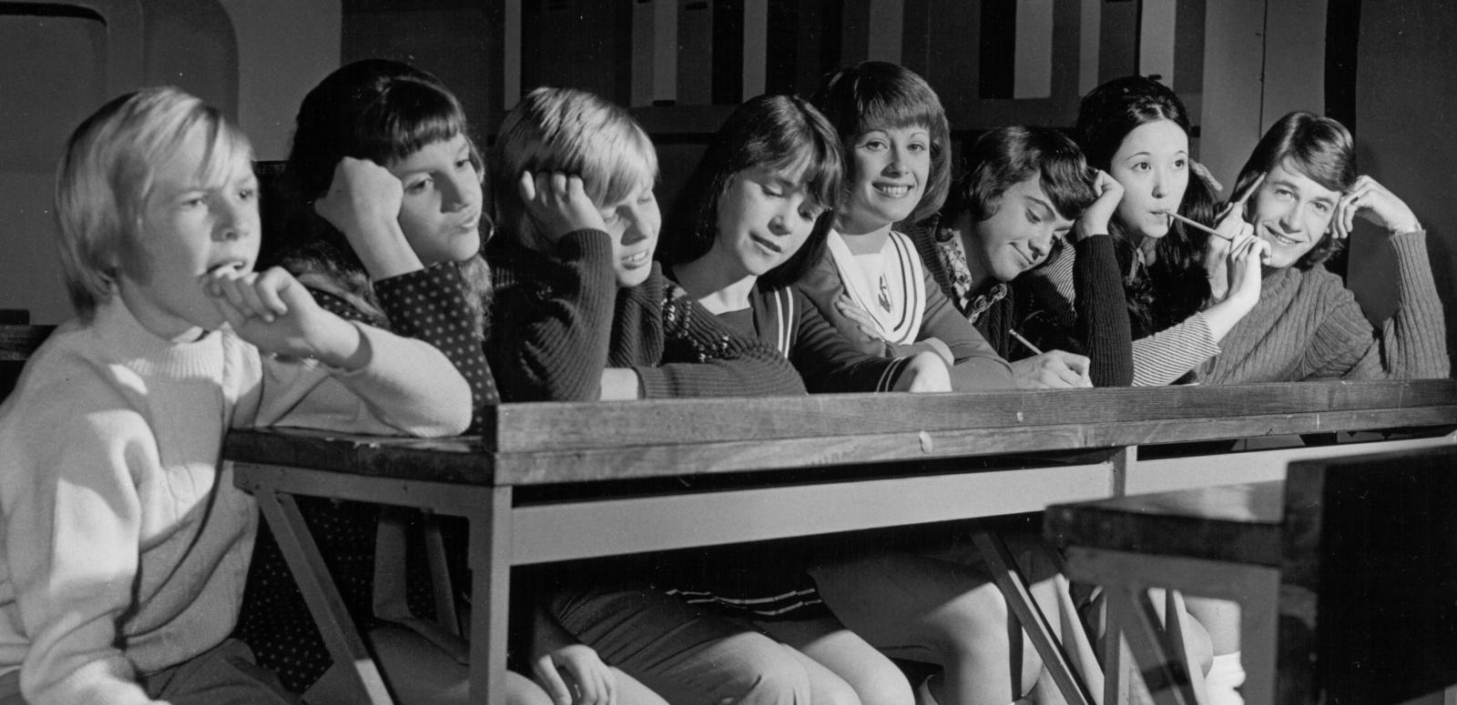 Young Talent Time 1971 Eight young people sit at a long table. One of them is Debra Byrne who is smiling at the camera.