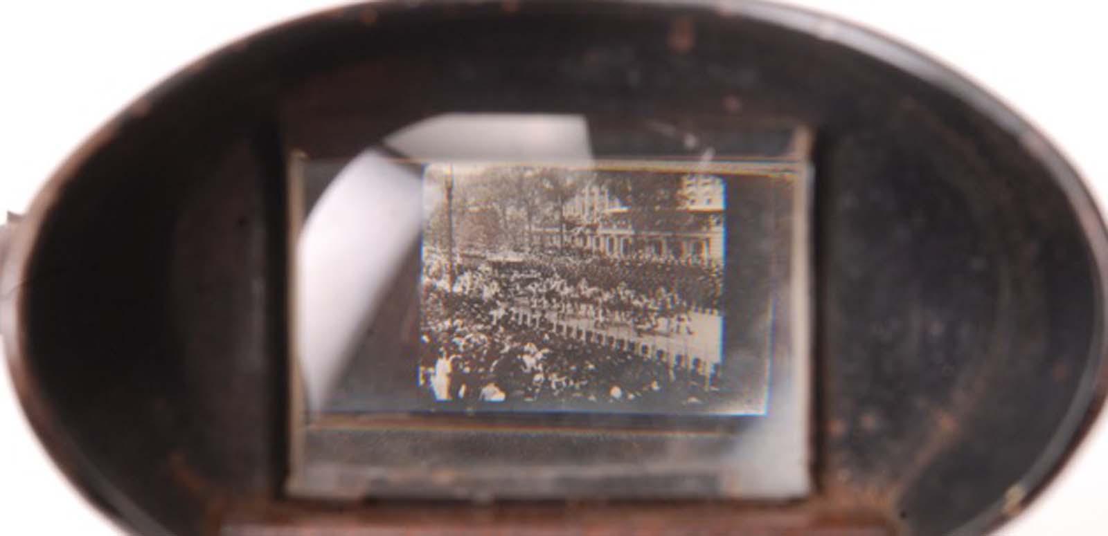 Looking through the viewing lens of a kinora at an image of a crowd scene. Looking through the viewing lens of a kinora at an image of a crowd scene.