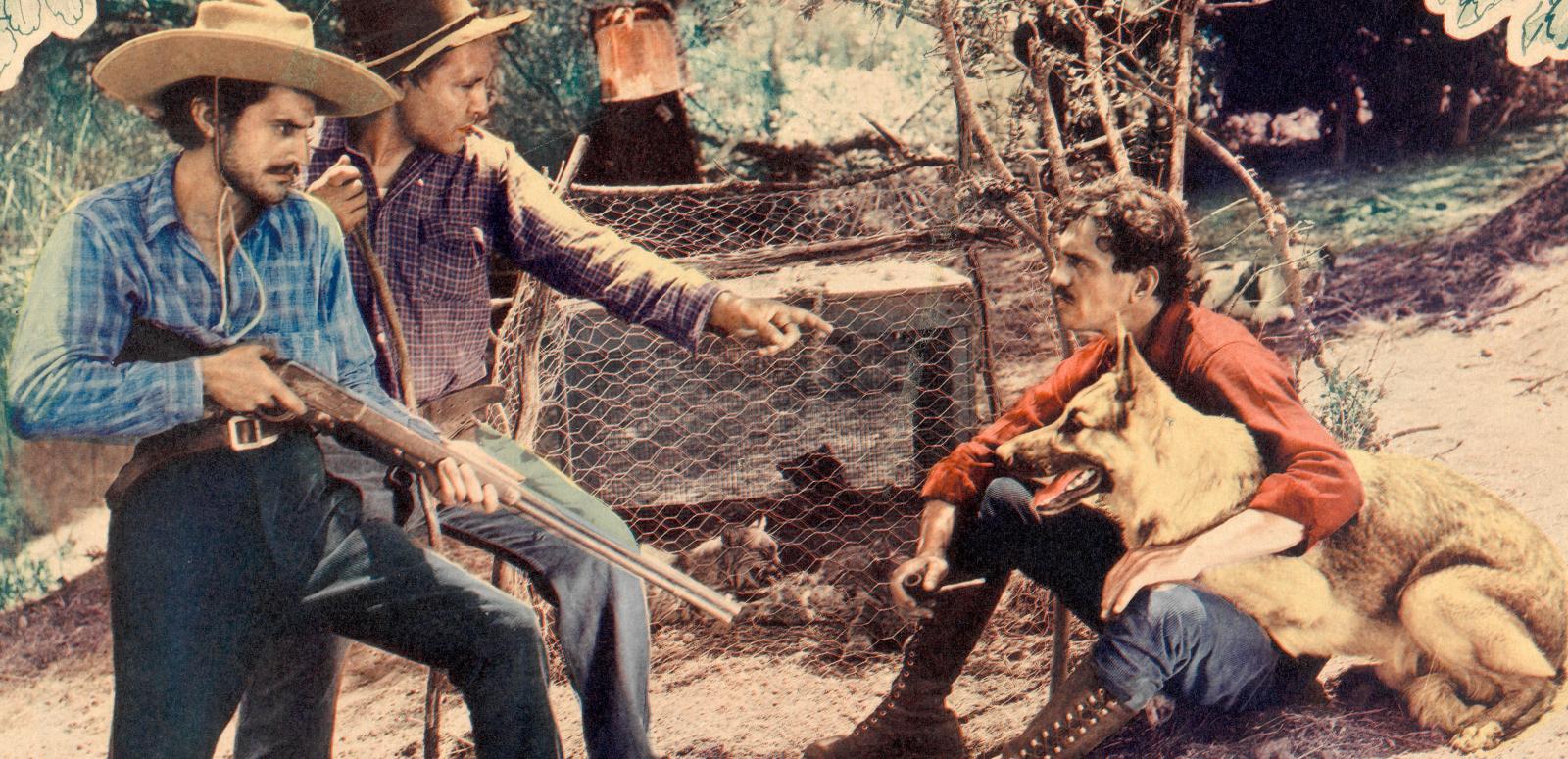 Trailing the Killer_1600x775 Two men hold rifles and stand over a man sitting on the ground with a dog
