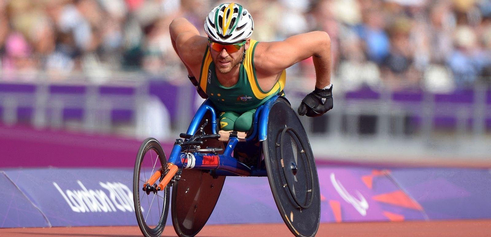 Kurt Fearnley Paralympics article hero Wheelchair racer Kurt Fearnley is captured racing at the London 2012 Paralympics. A packed stadium is blurred behind him.