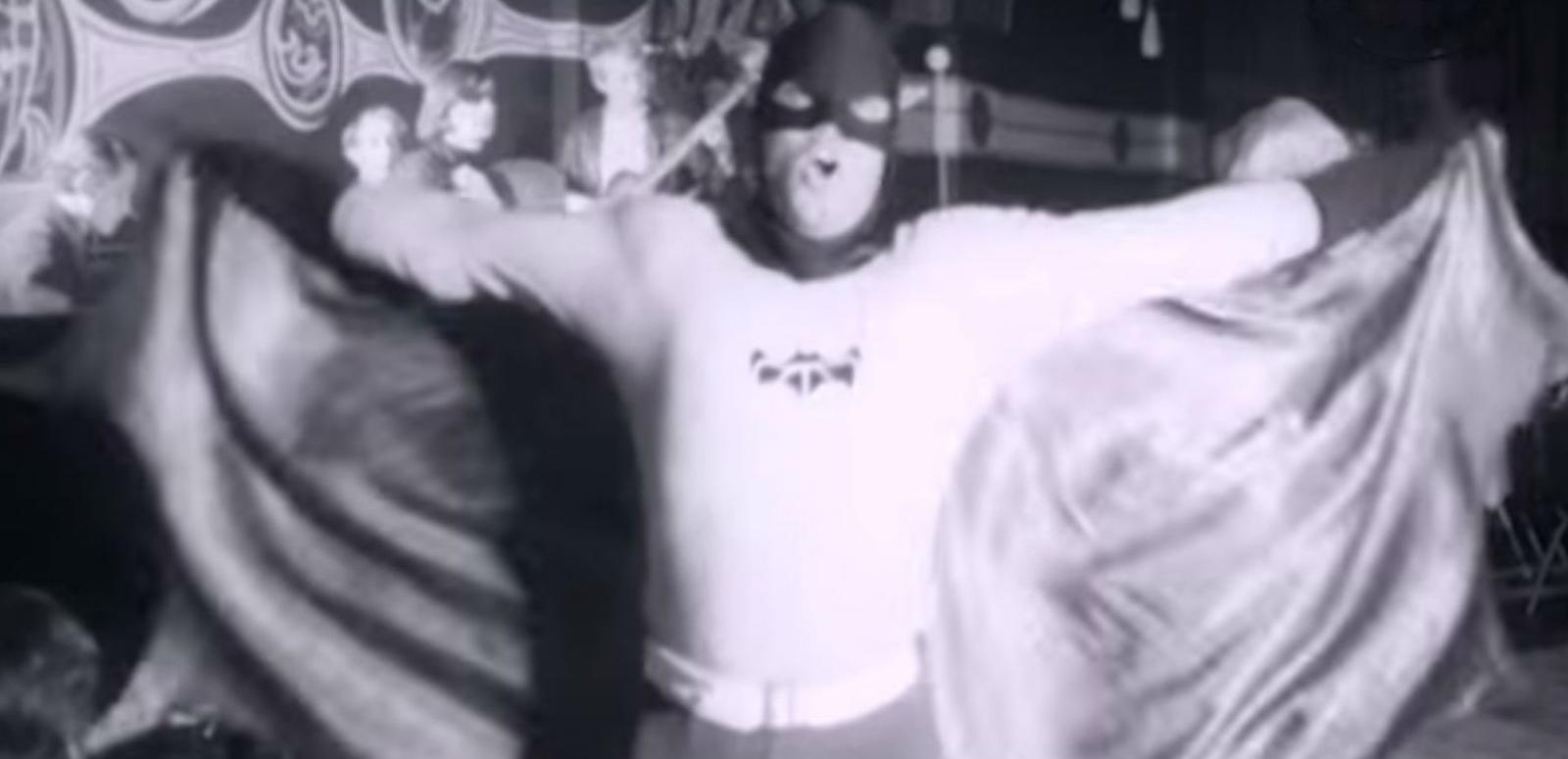 Batman au go-go hero image Man dressed up as batman dancing at a nightclub with go-go dancers.