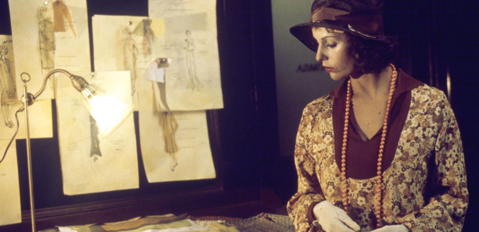 Caddie part 2 hero image Film still of Helen Morse as Caddie looking at drawings of women's dress designs in a studio.