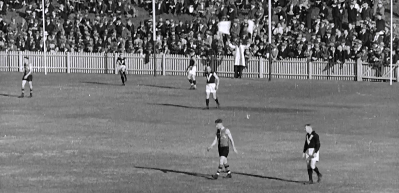 Black and white frame capture of the AFL goal umpire waving two flags signalling a six point score Black and white frame capture of the AFL goal umpire waving two flags signalling a six point score.