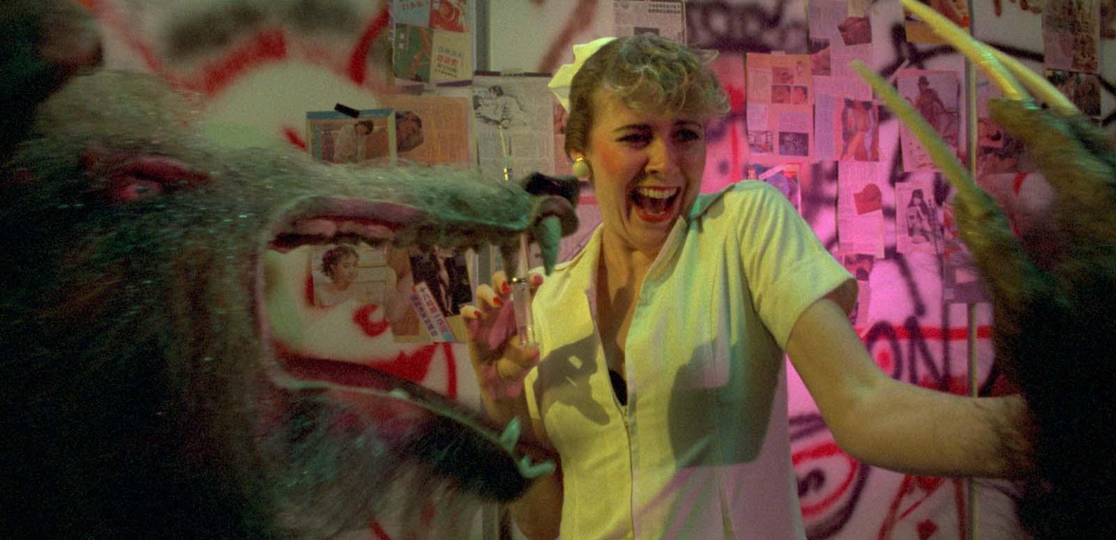 A nurse holding a syringe screams as she is menaced by a werewolf