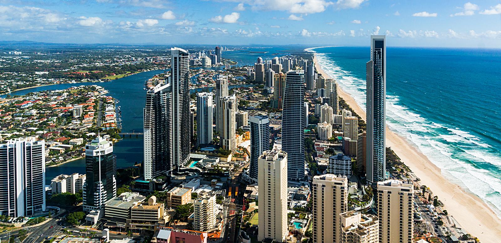 Gold Coast_1600x775 Aerial photo of the Gold Coast showing long stretch of beach, ocean and high rise buildings.