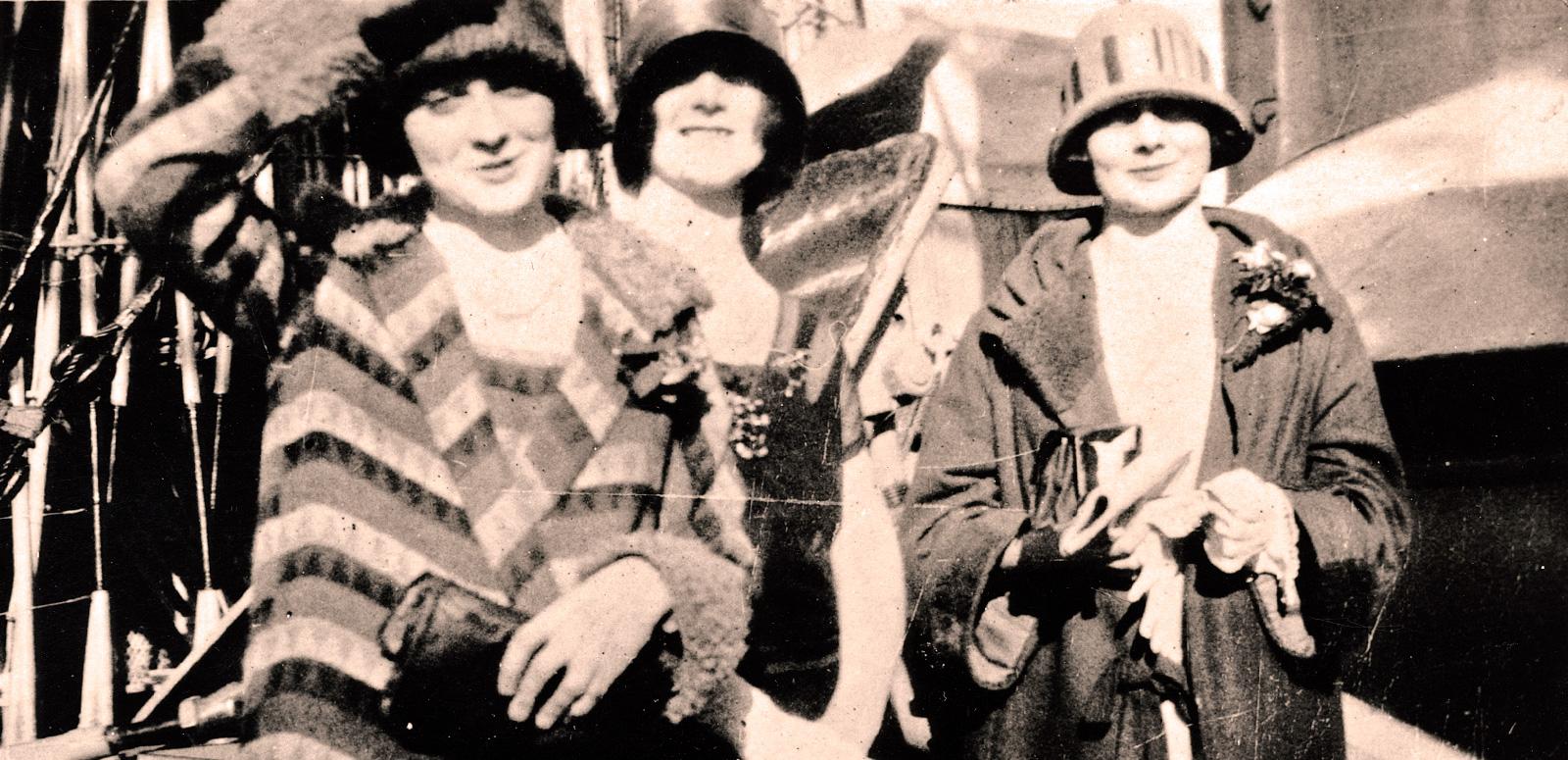 The McDonagh Sisters Collection hero image The McDonagh sisters, Isabel, Paulette and Phyllis, pictured from the waist up, wearing coats and hats and standing on the deck of a ship.
