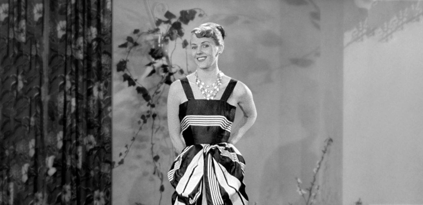 Vintage Fashion hero image A woman is modelling a dress. She is looking at the camera.