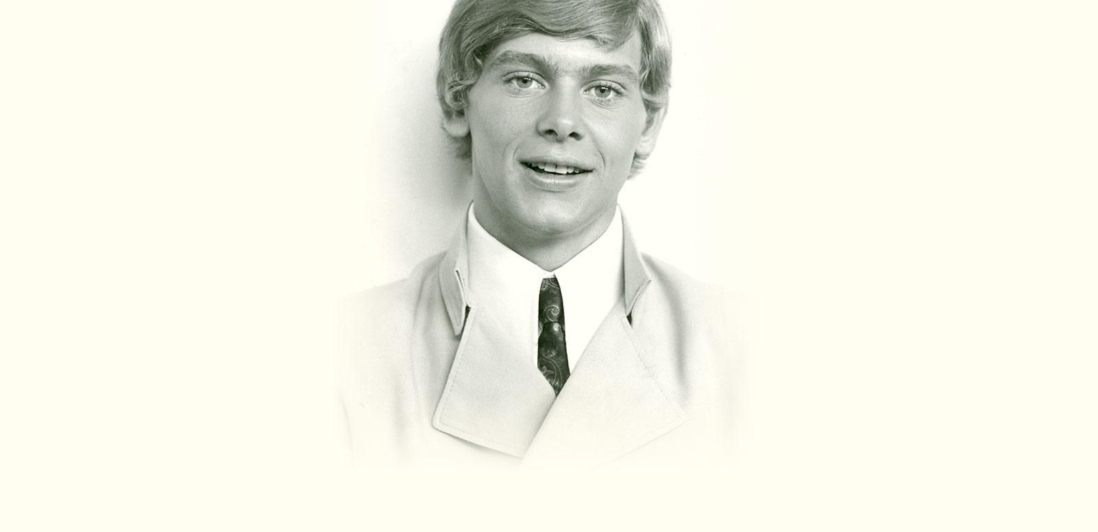 Head and shoulders publicity image of a young John Farnham, circa early 1970s, he's wearing a suit and tie looking directly at the camera.