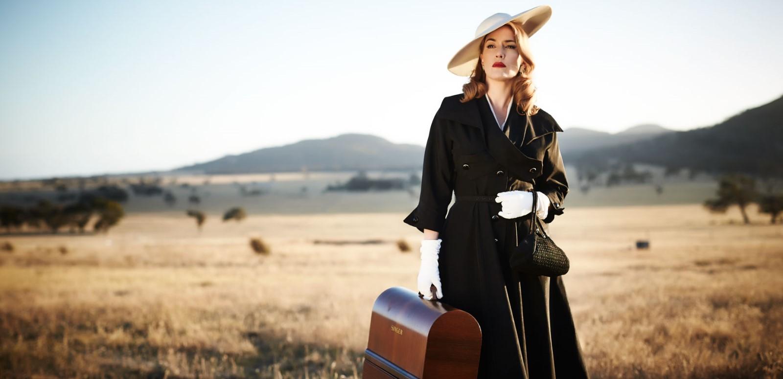 A woman in a black coat and hat holding a suitcase in the Australian outback A woman in a black coat and hat holding a suitcase in the Australian outback