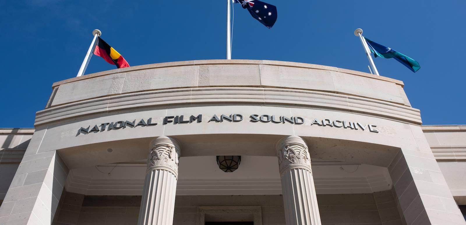 A close-up of the NFSA building in Canberra with the Aboriginal, Australian and Torres Strait Islander flags flying on top of the building