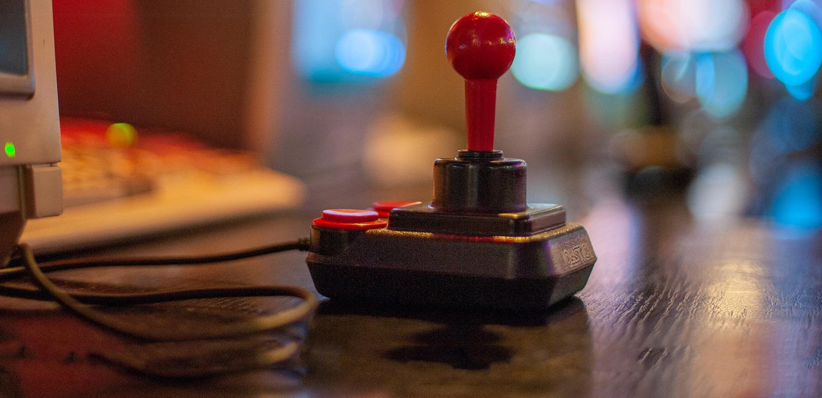 Close up of a video game joystick circa 1980s and the edge of a computer screen and keyboard.