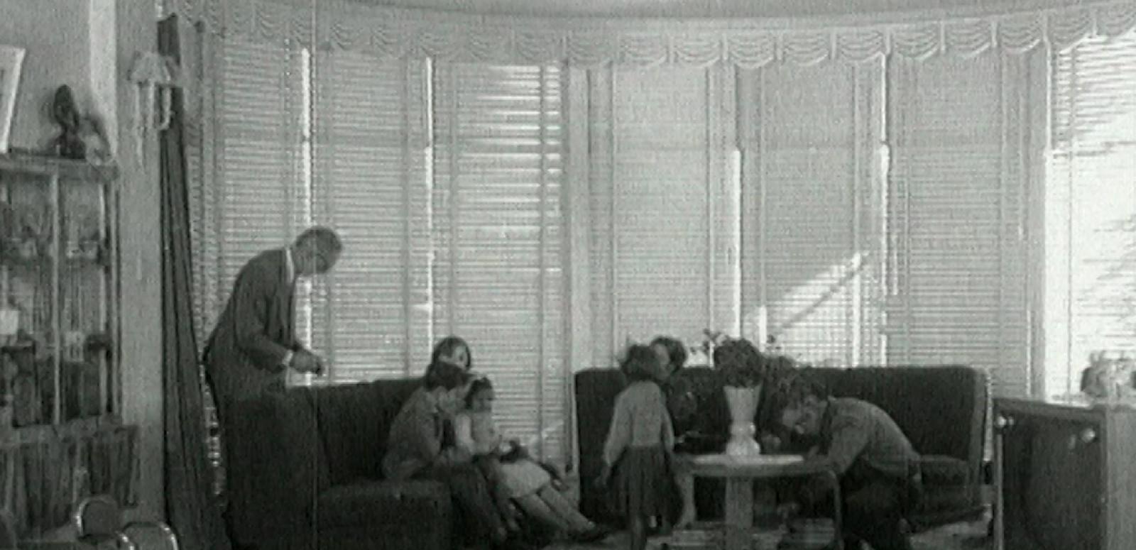 Wide shot of two little Aboriginal girls in the living room of their adopted white family