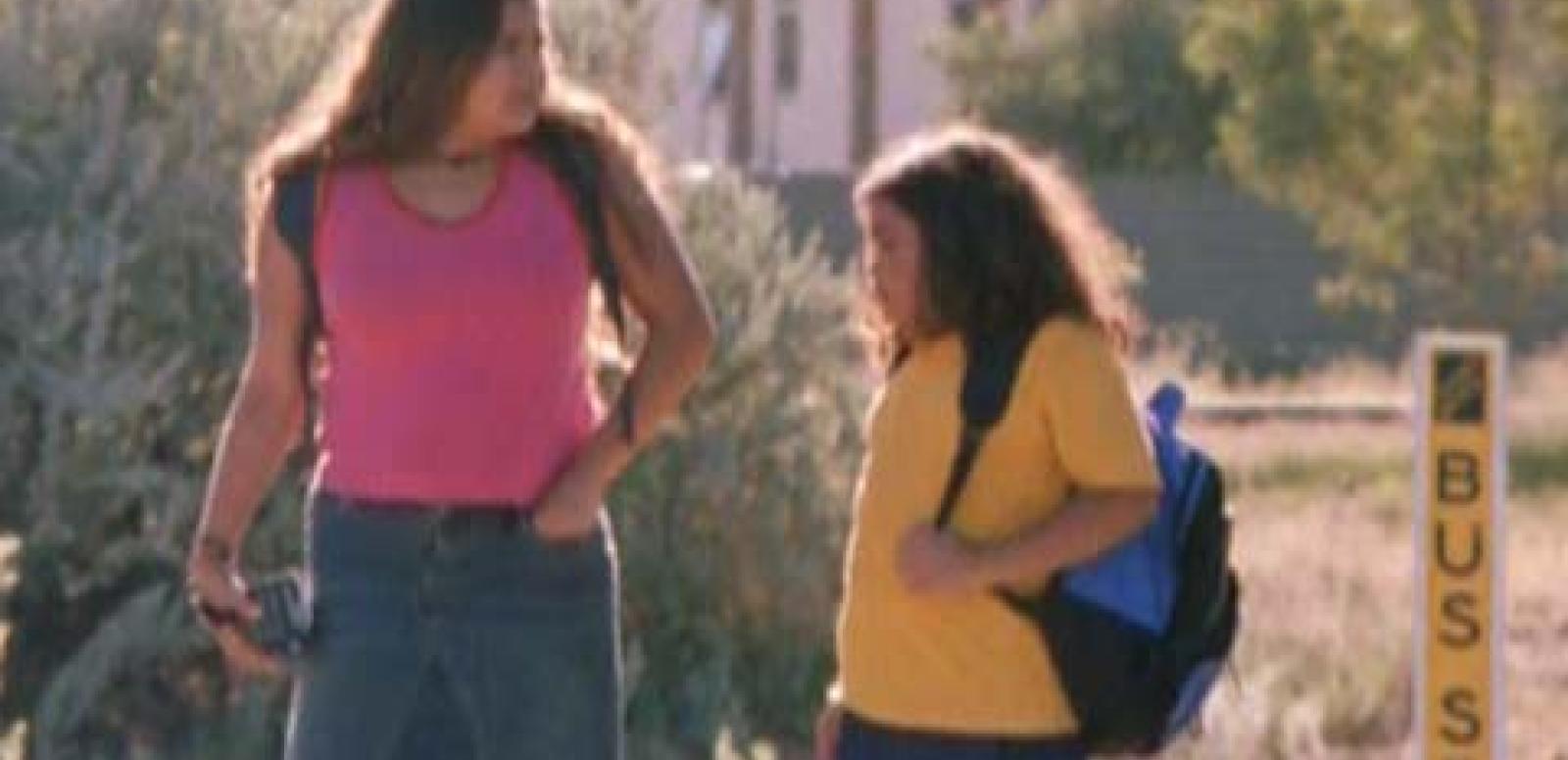 Two sisters walk to the bus stop on the way to school