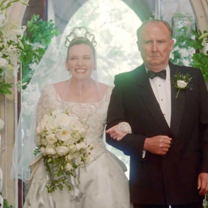 A scene from Muriel's Wedding - Muriel is in her wedding dress and is being walked down the aisle of a church by her father. 