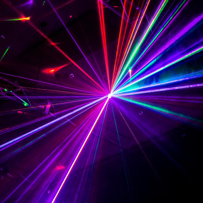 Red, purple and green laser beams extending from a central point in the exhibition Installations