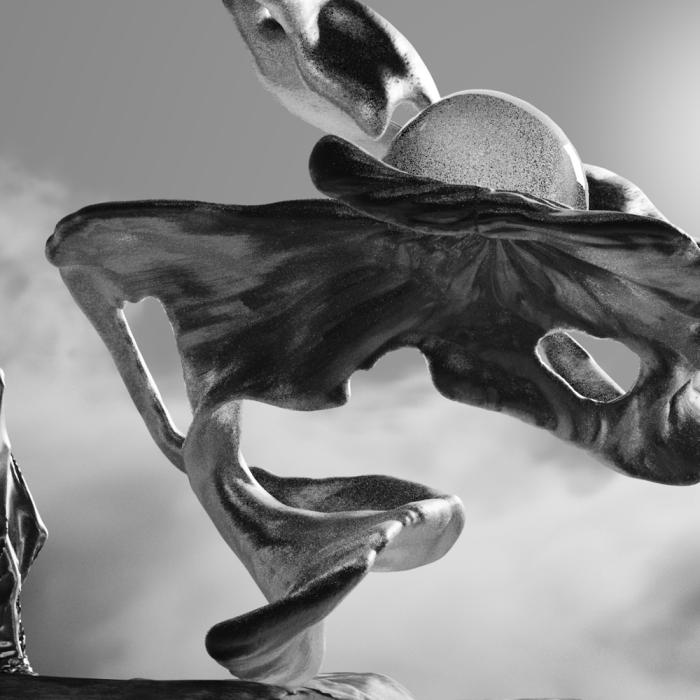 Detail from the art installation Inferno showing a figure draped in flowing cloth standing near a sculpture under a cloudy sky.