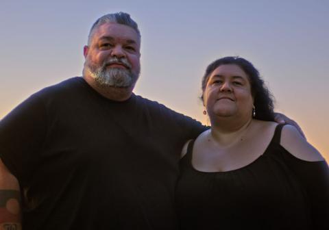 Filmmakers Adrian Russell Wills and Gillian Moody side by side, pictured with a setting sun in the background, in a scene from the film Kindred