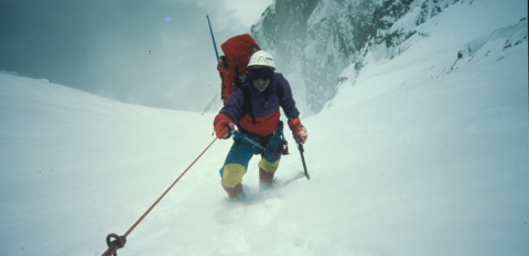 A climber making their way up a steep snow-covered mountain
