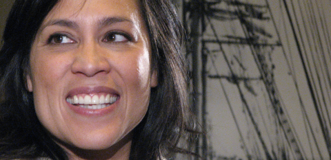 Kate Ceberano smiling in close-up against a drawing of a sailing ship