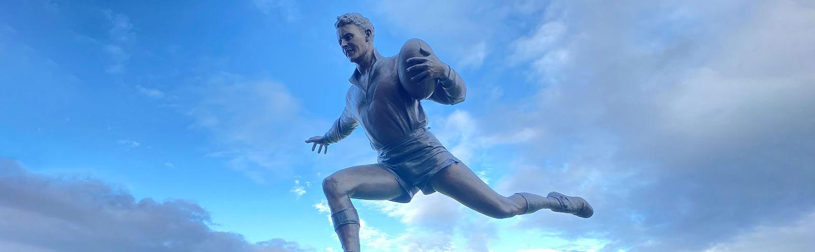 Statue of a man playing Aussie Rules football.