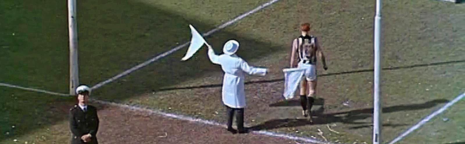 An AFL umpire waving flags