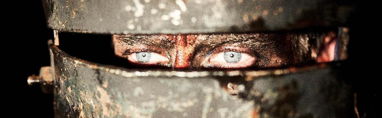 The eyes of Ned Kelly are visible through a slot in his armoured helmet in a scene from the movie True History of the Kelly Gang