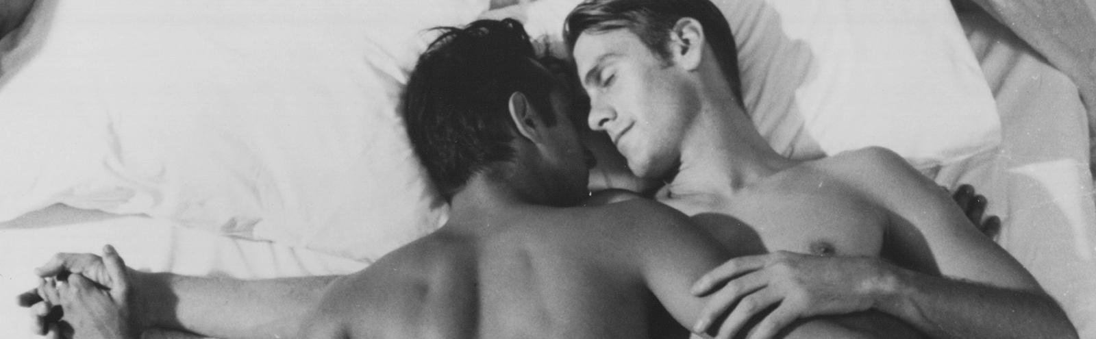 Two male lovers holding each other in bed in a scene from the Stephen Cummins short film Elevation