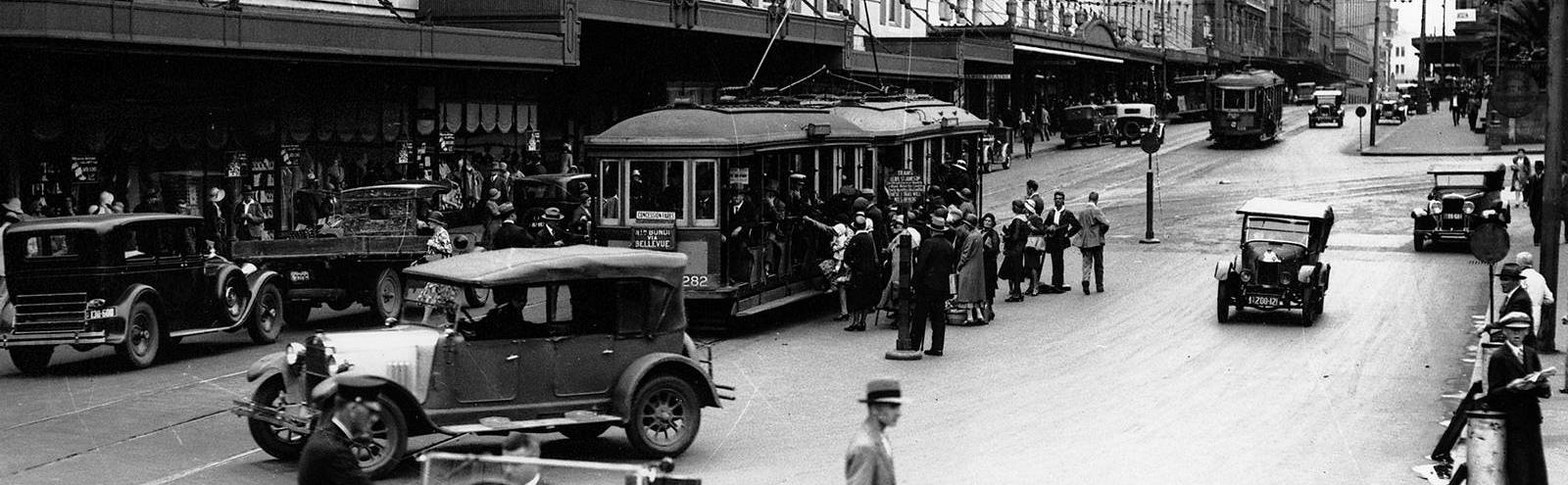 A view down Elizabeth Street in 1931 showing cars and trams and pedestrians crossing the road