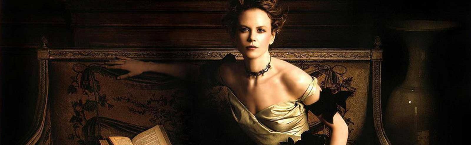 Nicole Kidman seated on an ornate bench with an open book beside her. She is dressed in period costume from the 1880s as a rich heiress in a scene from The Portrait of a Lady.