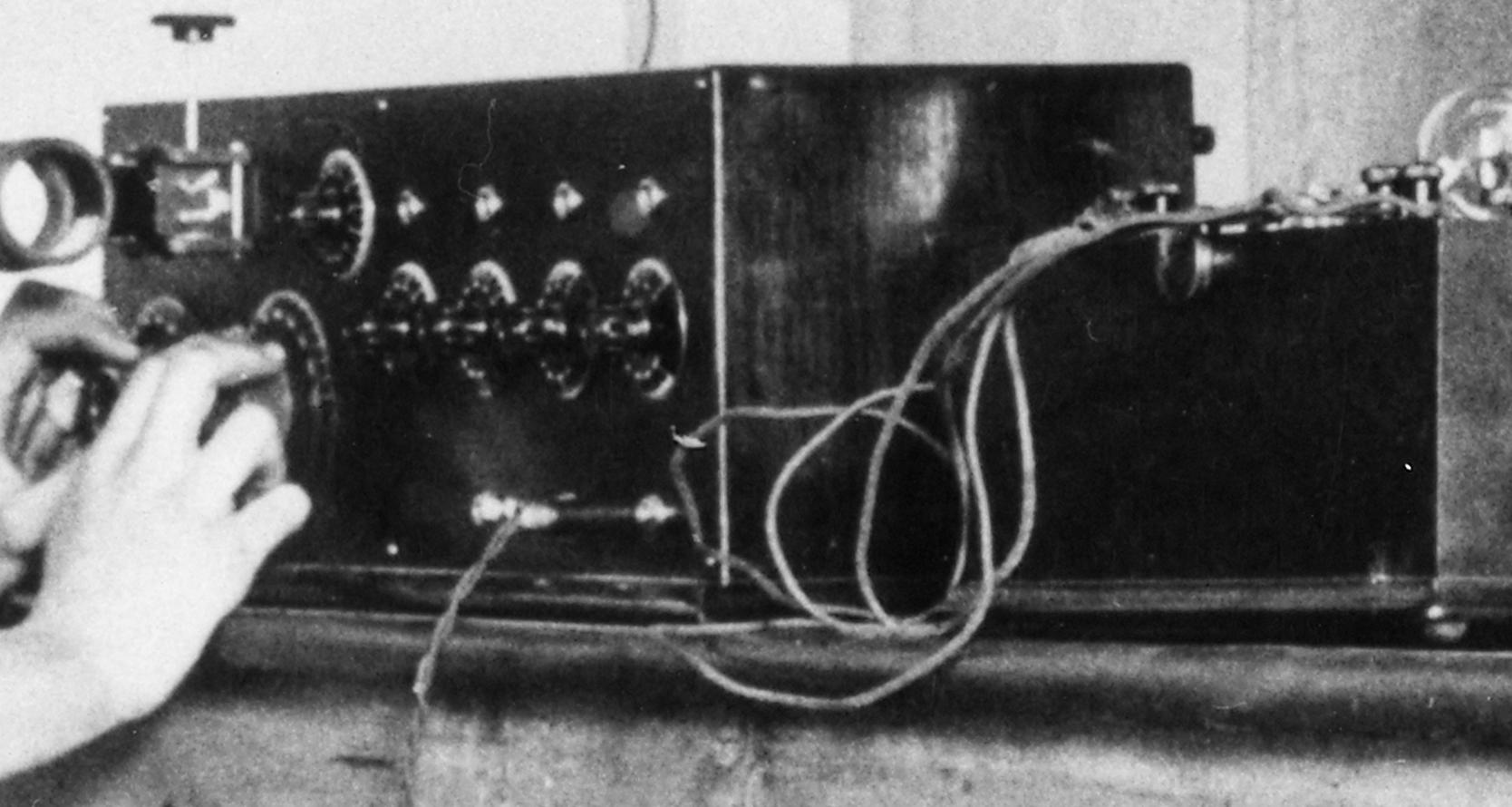 Close up of someone's hand turning dials on some radio equipment. 