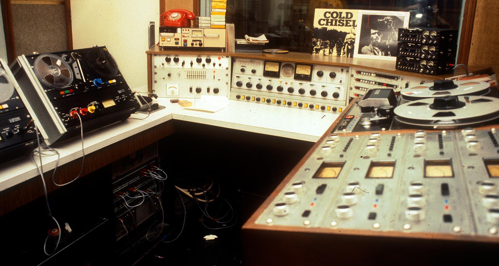 Inside a radio studio with tape decks and mixing desks.