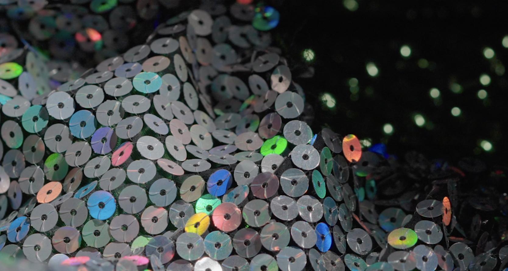 Close-up of sparkling silver sequins on green fabric