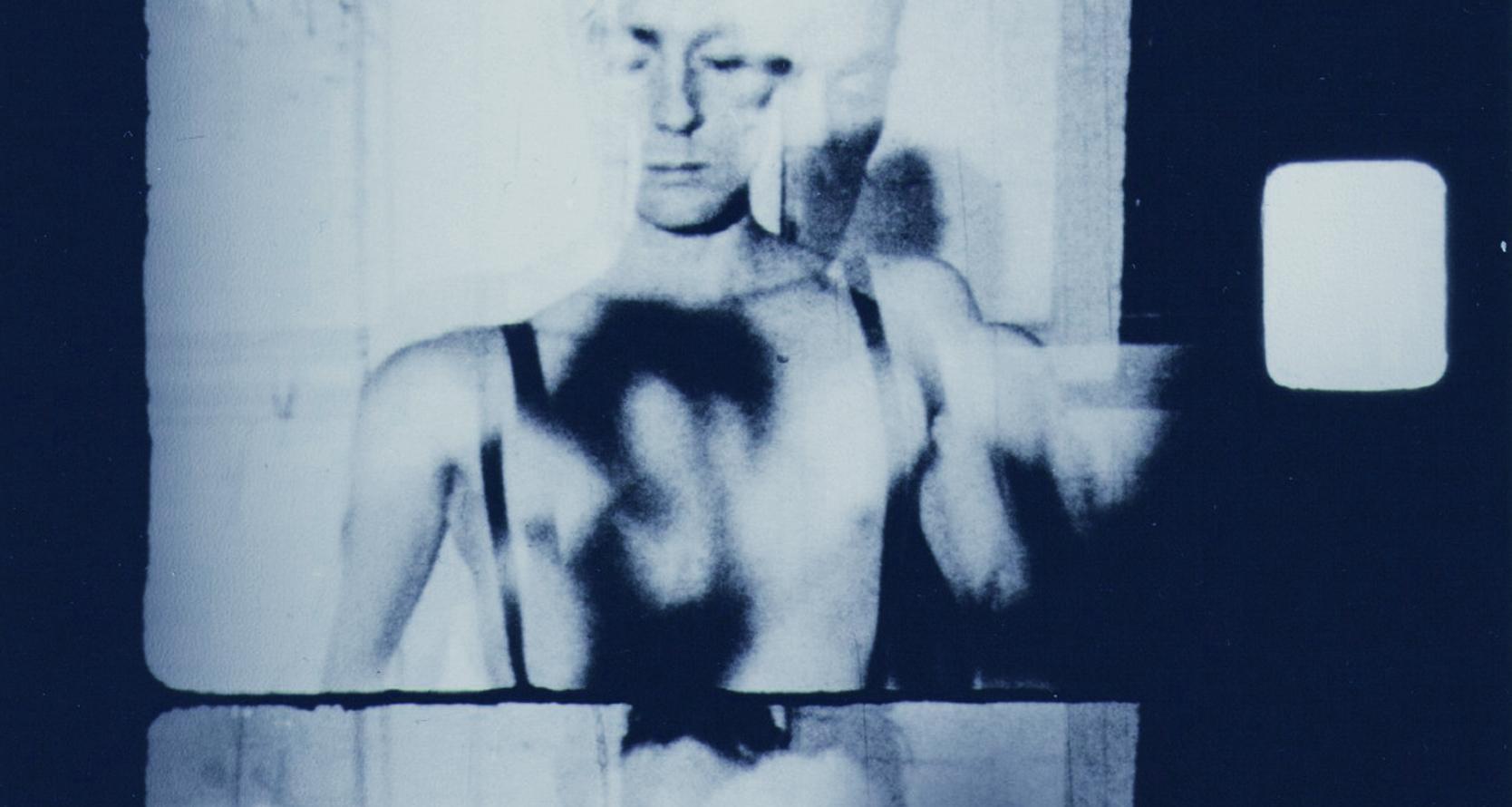 A segment from a film negative showing a man with a bare chest and closed eyes.