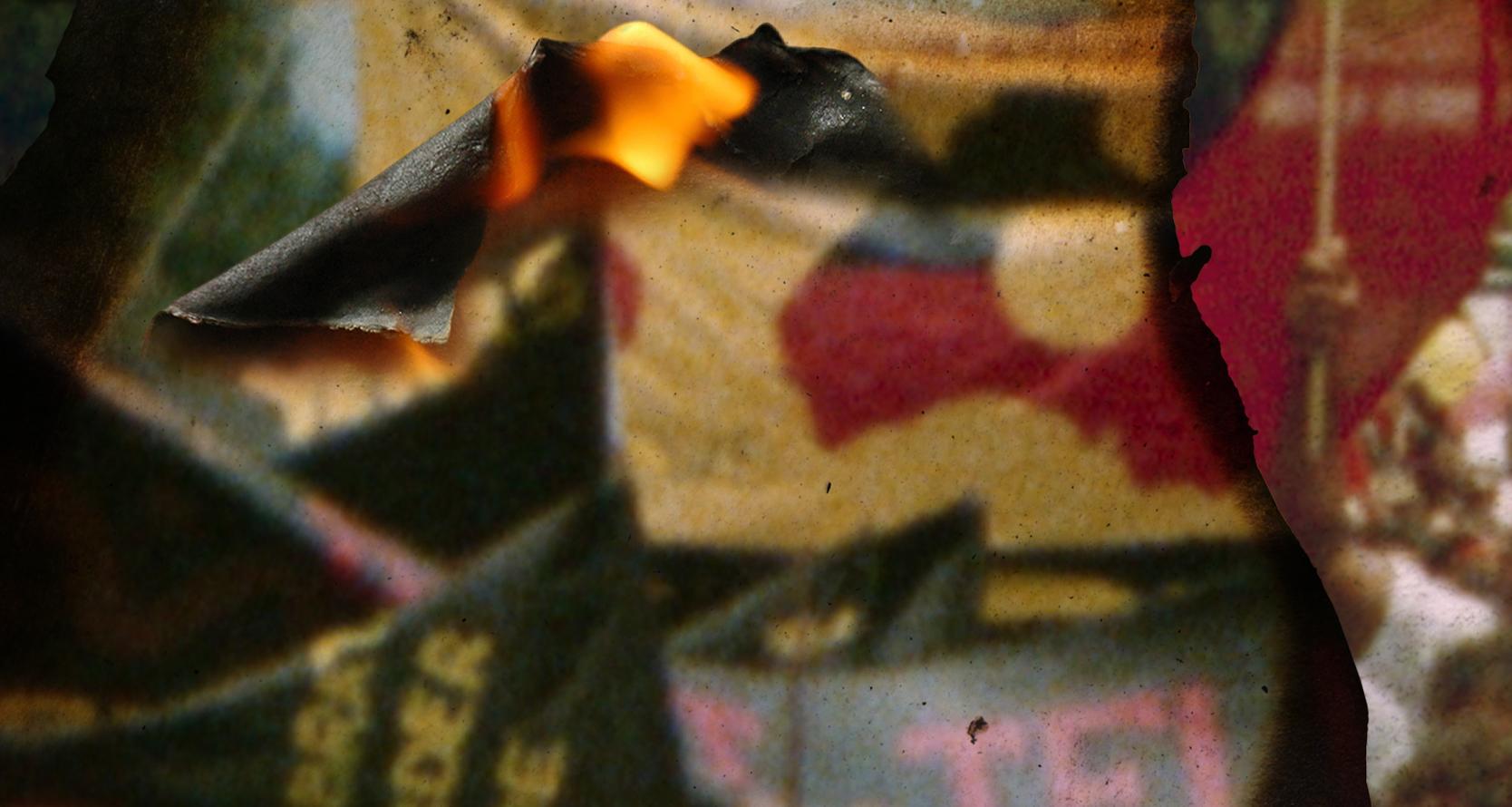 An archival image of an Aboriginal protest flag. The image has been treated so that the corner of it looks to be on fire and curling inwards