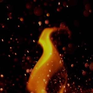 A lick of flame rises against a night sky filled with glowing embers