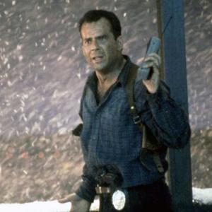 Actor Bruce Willis standing out in the snow at night time in a scene from Die Hard 2.