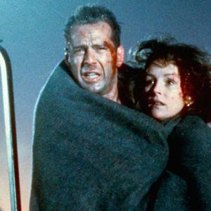 A man and woman, both with blood on their faces, embrace each other. They have a blanket wrapped around them. It's night time and snowing. 