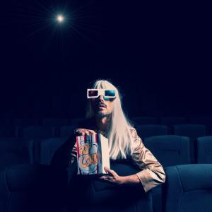 Person sitting in empty cinema wearing 3D glasses and eating popcorn