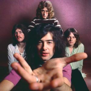 A posed studio portrait from 1969 of the four members of rock band Led Zeppelin. One of the band members stretches his hand out to the camera