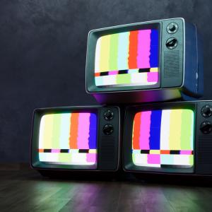 Three television sets stacked on top of each other displaying a coloured test pattern. 
