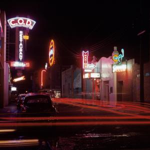 Photo of street at night lit up by the neon signs of various bars