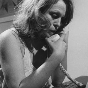 A distraught Jacki Weaver clutches the telephone receiver in a suburban home
